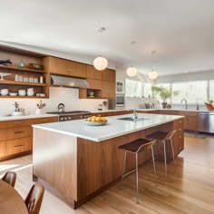 a large kitchen with wooden cabinets and white counter tops, along with two bar stools