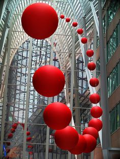 red balls are suspended from the ceiling in an atrium