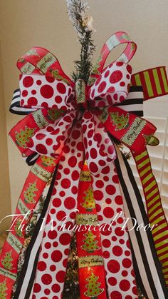 a christmas tree decorated with red and green ribbon, bow, and pine cone ornaments