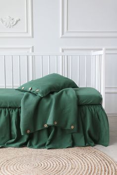 a green bed with ruffled bedspread and pillows on the floor in front of a white wall