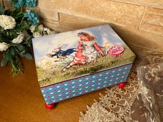 a decorative box sitting on top of a table next to flowers and lace doily