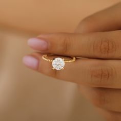 a woman's hand holding a gold ring with a white diamond on the side