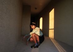 a woman kneeling down in an empty hallway