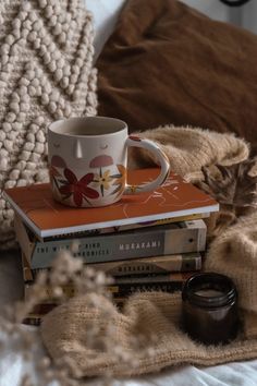 a stack of books and a cup on top of each other next to a blanket