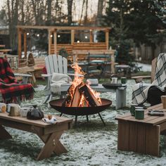 a fire pit surrounded by chairs and tables in the middle of a yard with snow on the ground