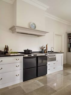 a large kitchen with white cabinets and black stove top oven in the middle of it