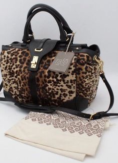 Stand out in the crowd with this stunning RAFE NEW YORK Bryn satchel/cross-body/shoulder bag. The leopard pattern in black makes a bold statement and is complemented by gold hardware on the flap with a turn knob closure. The bag is made of genuine Italian calf hair body with black leather accents, giving it a luxurious feel. Measuring 10.5" in height, 12" in width, and 5" in depth, this bag is the perfect size for everyday use. The interior lining is black and features enough space for all your essentials. With its versatile style, this bag can be worn as a satchel, cross-body, or shoulder bag, making it a must-have addition to any wardrobe. Hello Lover, People Clothes, Animal Fur, The Leopard, Leather Accents, Leopard Animal, Shopping Ideas, Leopard Pattern, Calf Hair