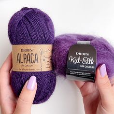 two balls of purple yarn are being held up