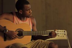 a man sitting on a chair holding an acoustic guitar