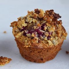 a muffin with crumbled toppings sitting on top of a white surface