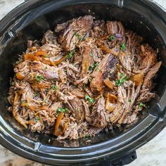 shredded meat in the slow cooker with parsley on top and carrots around it