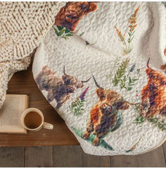 an animal themed blanket on a wooden floor next to a cup of coffee and book