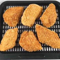 four pieces of fried chicken sitting on top of a grill