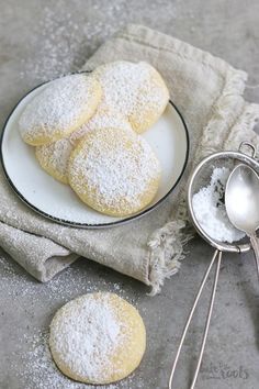 powdered sugar cookies on a plate with a measuring spoon