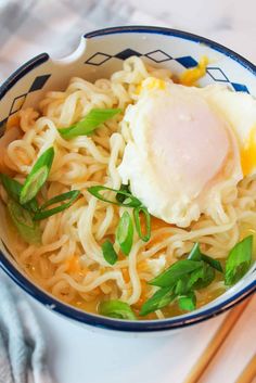 a bowl of noodles with an egg on top and chopsticks next to it