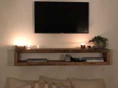 a flat screen tv mounted above a wooden shelf