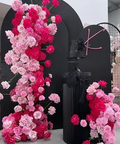 pink and red flowers on display in front of a black sculpture