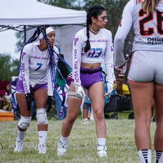 three girls in purple shorts and white shirts are playing frisbee on the field