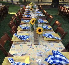 a long table is set with sunflowers and blue gingham napkins