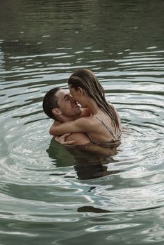 a man and woman are in the water hugging each other with their arms around each other