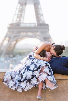 a man and woman are hugging in front of the eiffel tower, paris