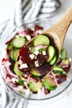 a salad with cucumbers, radishes and feta cheese in a glass bowl