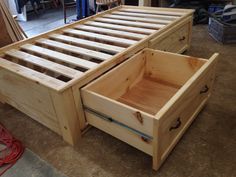 a wooden bed frame with drawers on the bottom