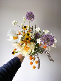 a person is holding a bouquet of flowers in their left hand, with other flowers on the right