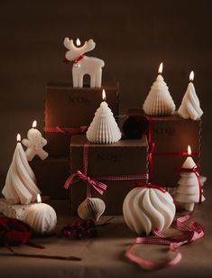 some candles that are sitting in front of boxes with christmas decorations on top of them