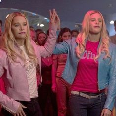 two young women standing in front of a group of people with pink paint on their faces