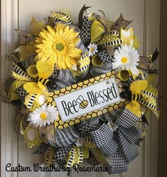 a yellow and black wreath with sunflowers on the front door that says bee's blessing