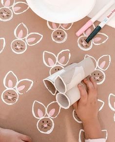 a child's hand holding a roll of toilet paper with bunny ears on it