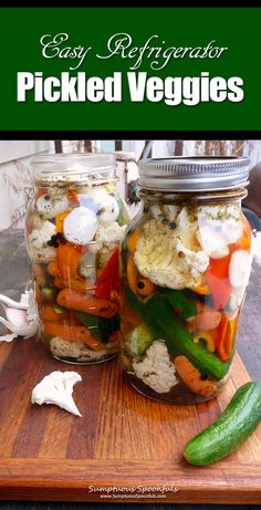 two jars filled with pickled veggies sitting on top of a wooden cutting board