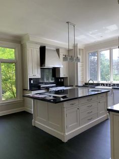 a large kitchen with black counter tops and white cabinetry, along with an island in the middle