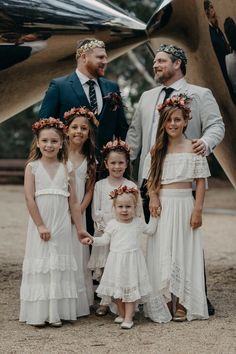 a group of people standing next to each other in front of a metal structure wearing flower crowns