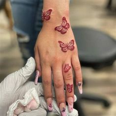 a woman's hand with butterfly tattoos on her left wrist and pink manicures