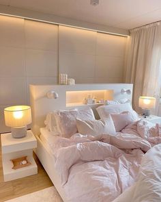 a white bed sitting in a bedroom next to a lamp on a night stand and a window