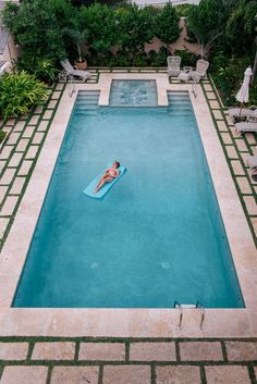 a woman is floating in a pool on a floatie board while sitting at the edge