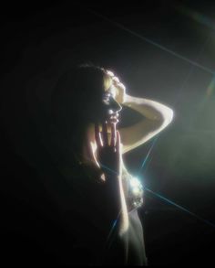 a woman with her hands on her face in front of the sun shining behind her