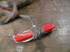 a red object is tied to a piece of string on a wooden table next to some yarn