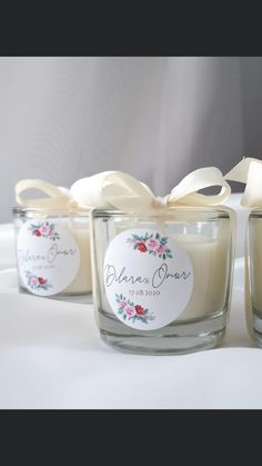 three small glass jars filled with candles on top of a white cloth covered tablecloth