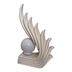 a white vase sitting on top of a table next to a ball and some feathers