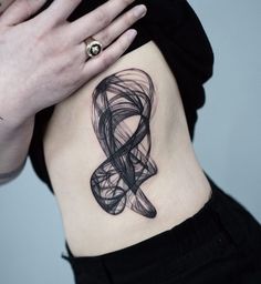 a woman with a tattoo on her stomach has a black and white ribbon in the shape of a heart