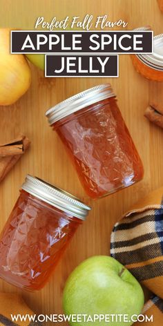 two jars filled with apple cider jelly on top of a wooden table next to apples