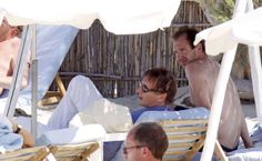 two men and a woman lounging on the beach