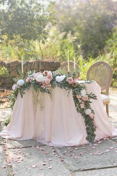 the table is covered with pink flowers and greenery