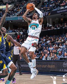 a basketball player jumping up to dunk the ball in front of two other players