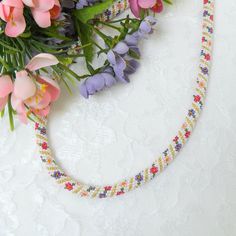 a braided necklace with flowers on it and some other items in front of it