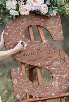 a wooden easel with writing on it and flowers in the top right hand corner