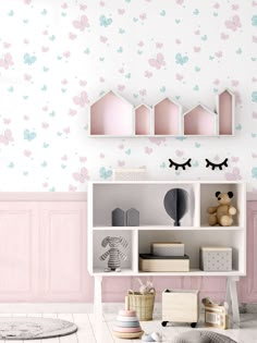 a child's room with pink and blue wallpaper, white bookcases and toys